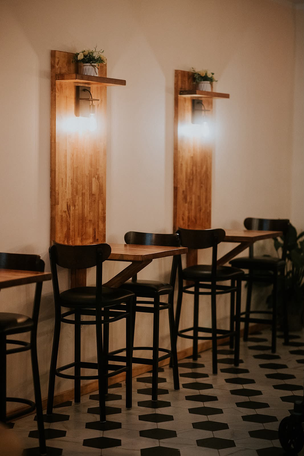 Custom-built wood wall sconces, bar tables and stools on hex tile flooring
