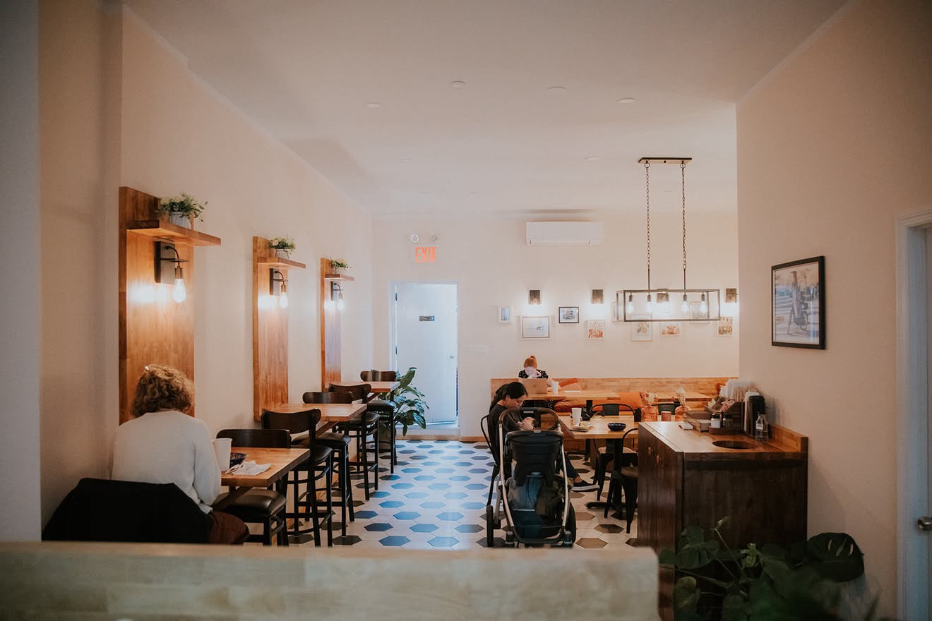 Finished cafe interior with warm lighting, custom wood booths and hex tile floor