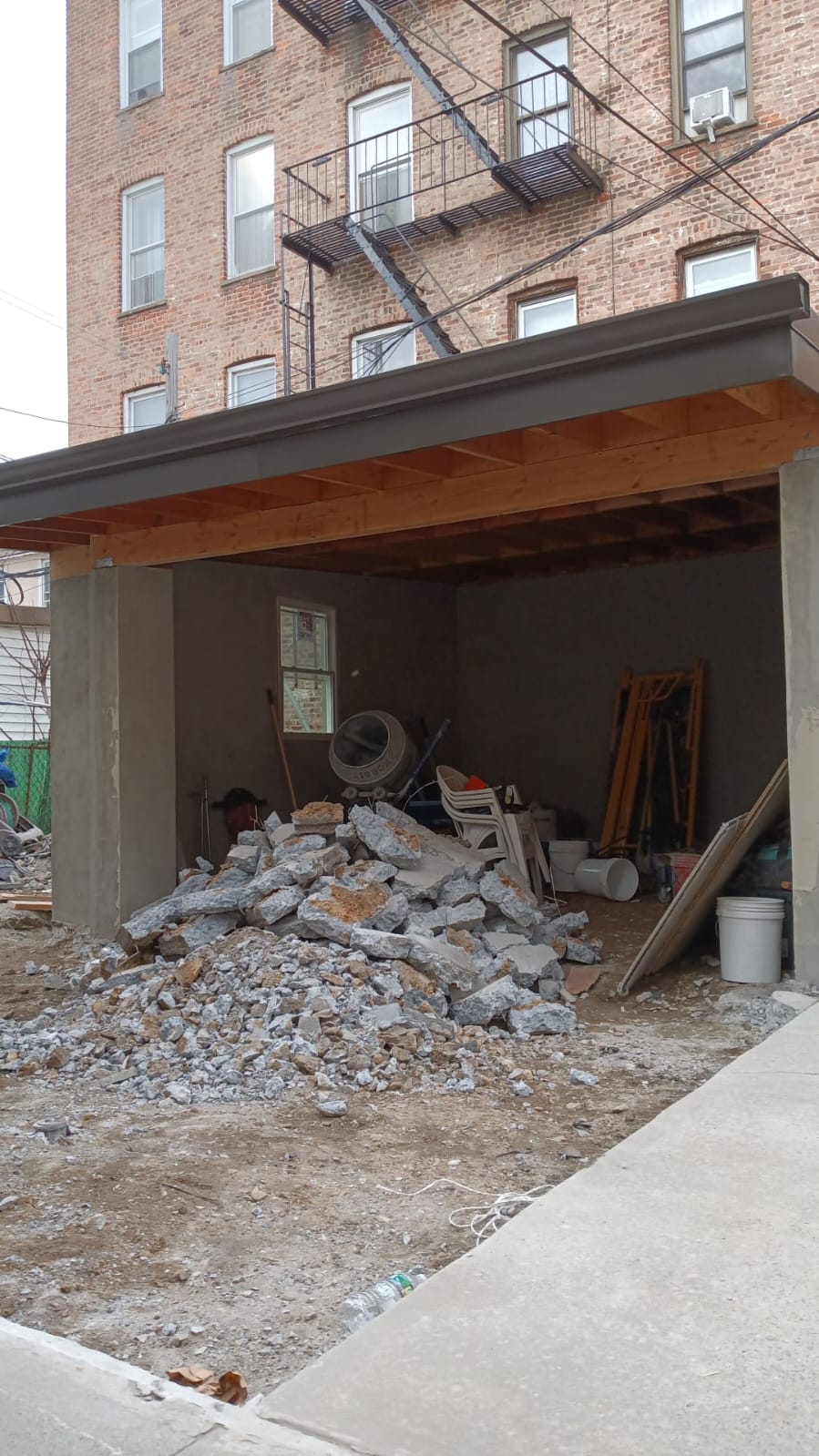 Backyard garage in progress with a new timber and metal roof over ongoing concrete demolition
